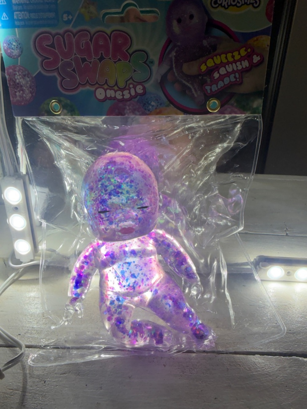 Squeeze Glittery Clear Onesie Doll in Purple and Blue